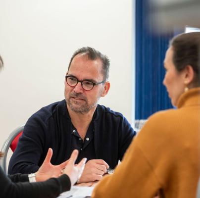 A man and two women sit together in a meeting, engaged in discussion