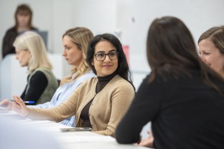 Three women sit together in a meeting, discussing ideas and collaborating