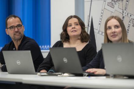 A man and two women sit together in a meeting, engaged in discussion