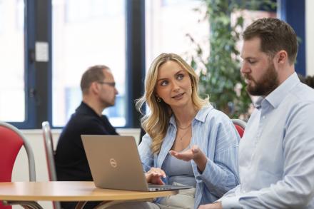 A man and two women sit together in a meeting, engaged in discussion