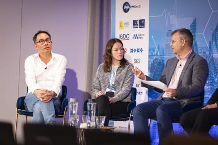 Three people sat together on stage hosting a panel discussion at BioTrinity 2025 event.