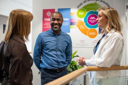 A man and two women stand together having a discussion