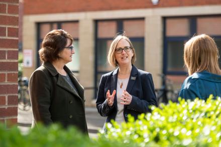 Three women outside an office building having a discussion