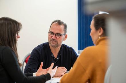 A man and two women sit together in a meeting, engaged in discussion